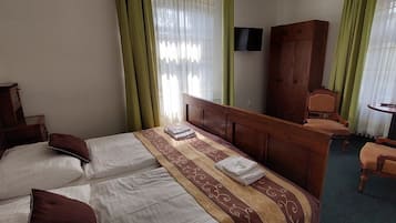 Una habitación de hotel con una cama, un armario de madera, una mesita y una silla.