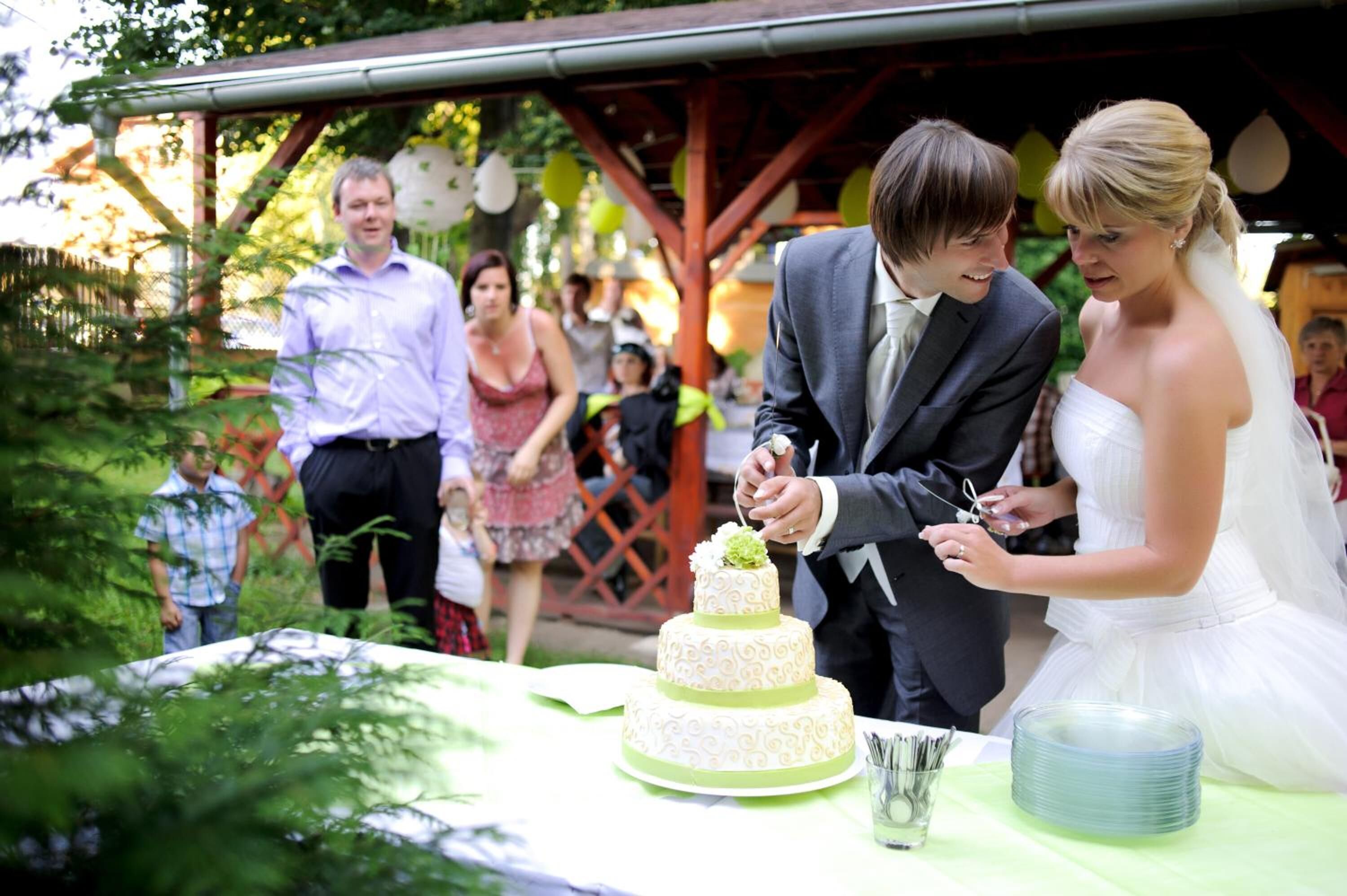 A wedding ceremony with a couple cutting a three-tiered cake.