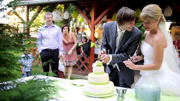A wedding ceremony with a couple cutting a three-tiered cake.