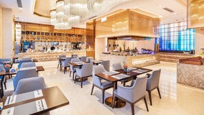 Un moderno vestíbulo de hotel con zona de bar, arreglos de asientos y un amplio ventanal con vidrio azulado.