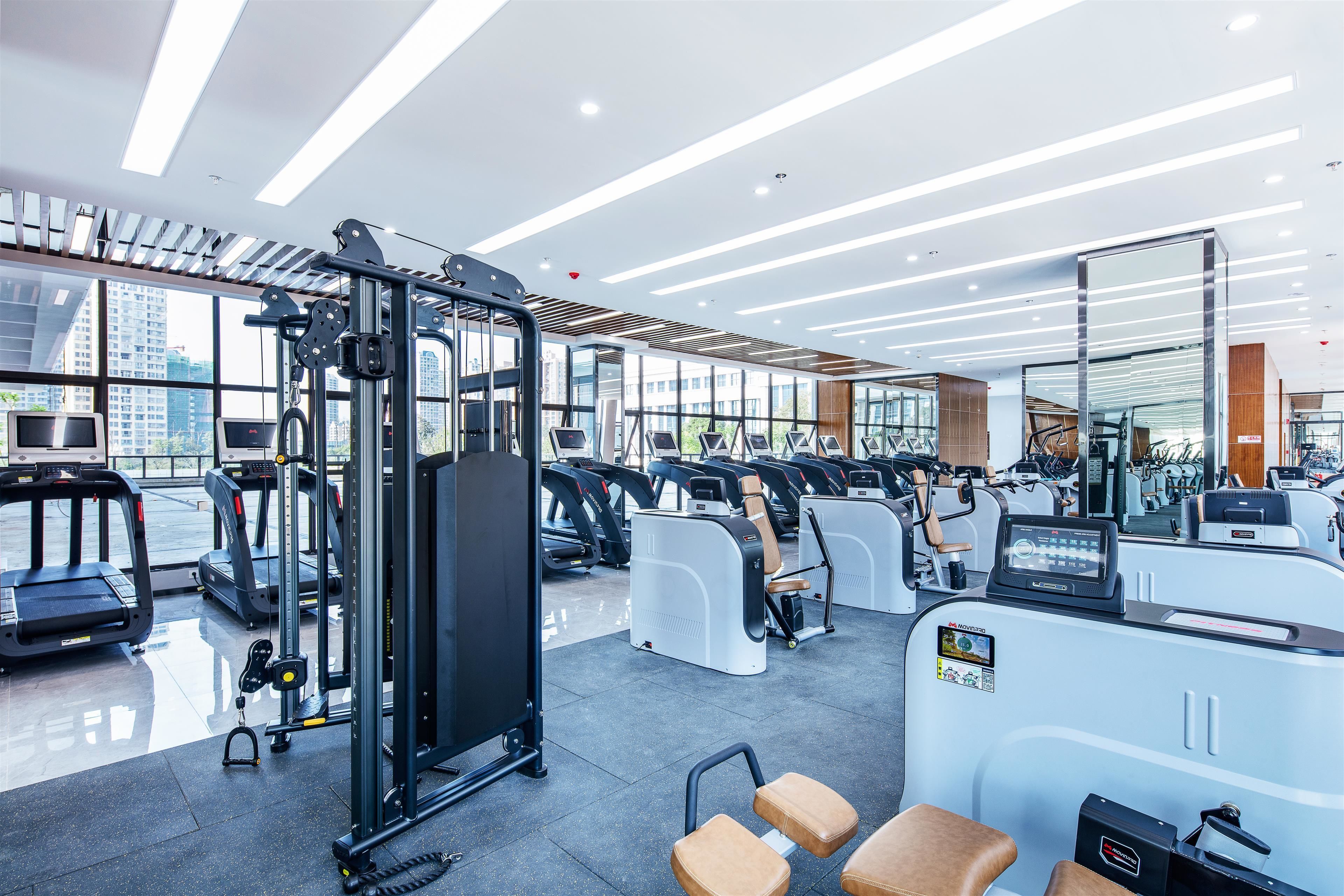 Ein modernes Fitnessstudio mit Laufbändern, Crosstrainern und Gewichten.