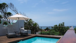 A poolside area with two lounge chairs and an umbrella, overlooking a scenic view. - Ocean Vista Boutique Guest House (Umhlanga)