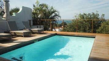 A swimming pool with lounge chairs and a wooden deck.