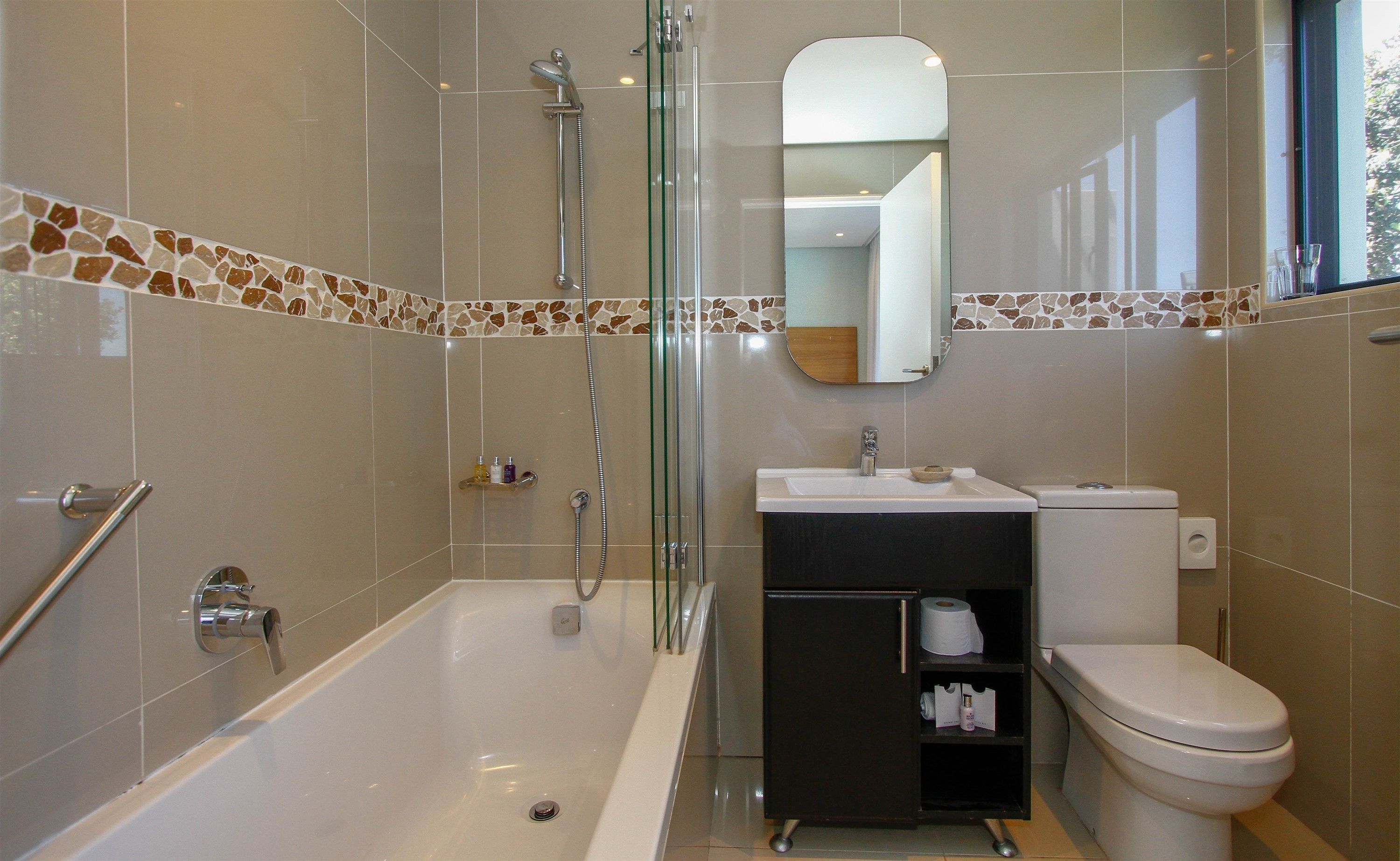 Une salle de bain moderne avec une douche à parois de verre, une baignoire blanche, un meuble-lavabo noir avec un miroir et des toilettes.