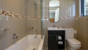 A modern bathroom with a glass-enclosed shower, a white bathtub, a black vanity with a mirror, and a toilet.