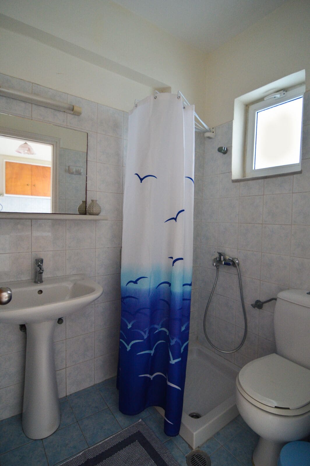 Un baño con lavamanos, inodoro, ducha y ventana.