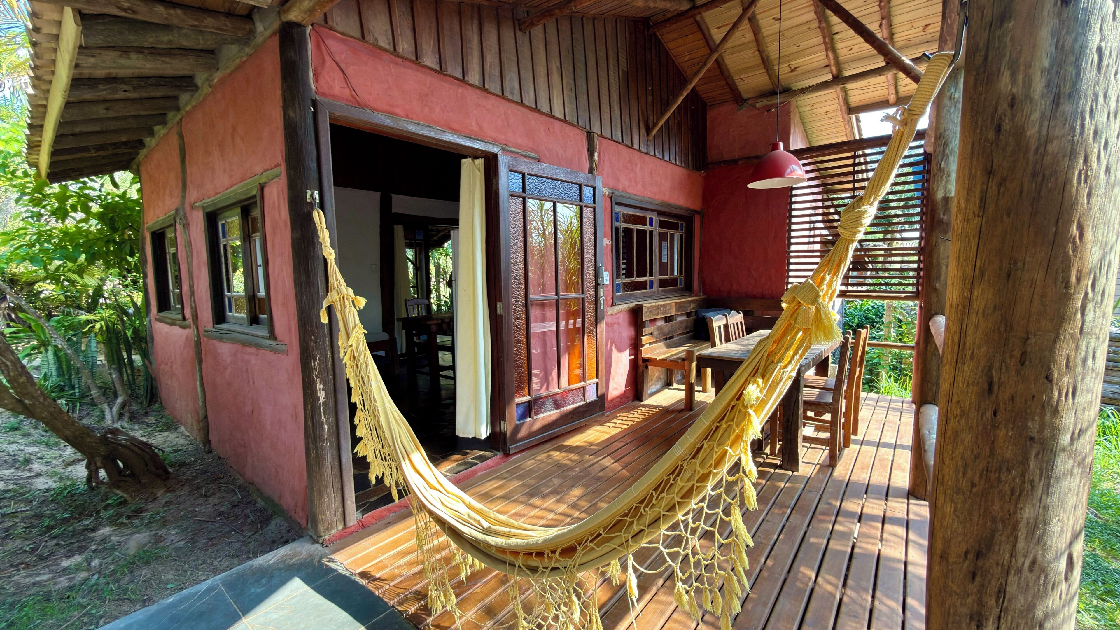 A wooden deck with a hammock, a wooden table, and chairs.