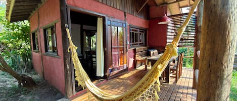 A wooden deck with a hammock, a wooden table, and chairs.