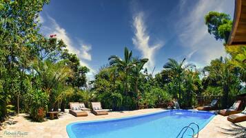 Una piscina al aire libre, sombrillas, sillones reclinables de piscina