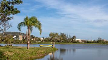 Un lago tranquilo con un bote, palmeras y casas al fondo.