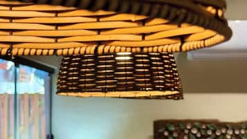 A room with a hanging light fixture, a window with blinds, and a buffet table with various food items.