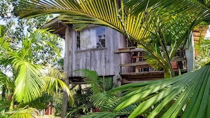 A wooden house with multiple levels, surrounded by lush greenery and palm trees. - Pousada Morro das Palmeiras (Imbituba)