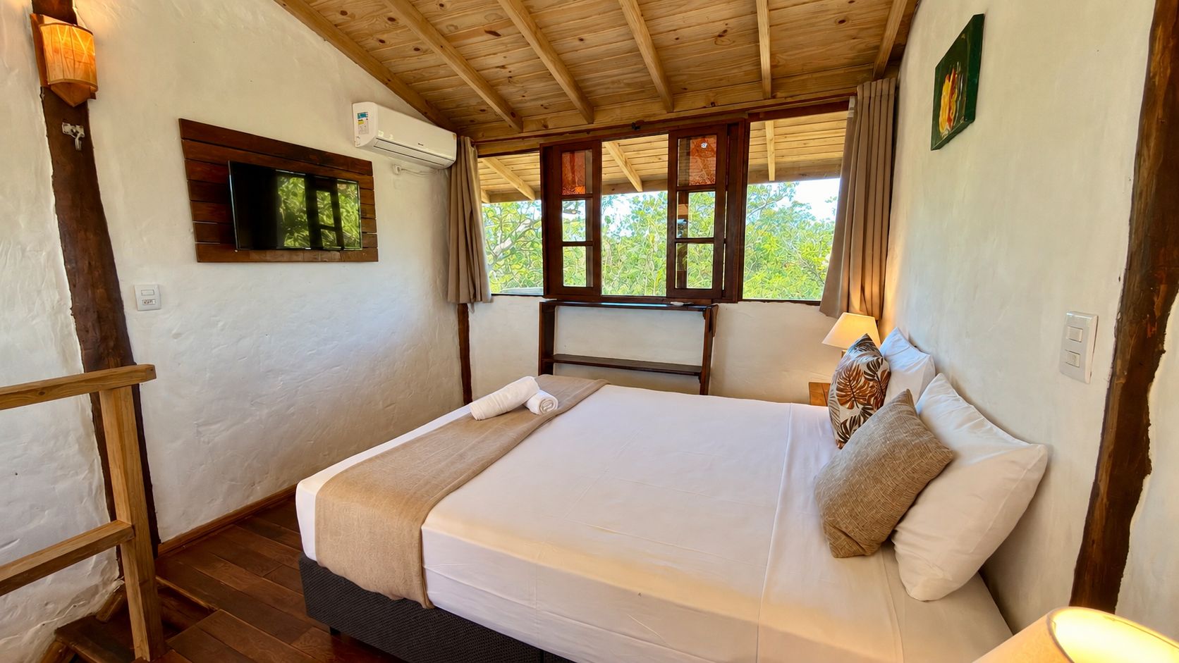 Una cama individual con cabecera de madera, una lámpara de noche y una ventana con cortinas.