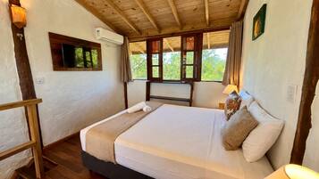 Una cama individual con cabecera de madera, una lámpara de noche y una ventana con cortinas.