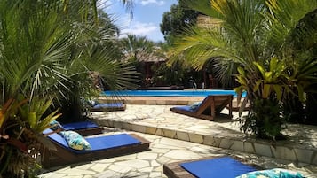 Una piscina al aire libre, sombrillas, sillones reclinables de piscina