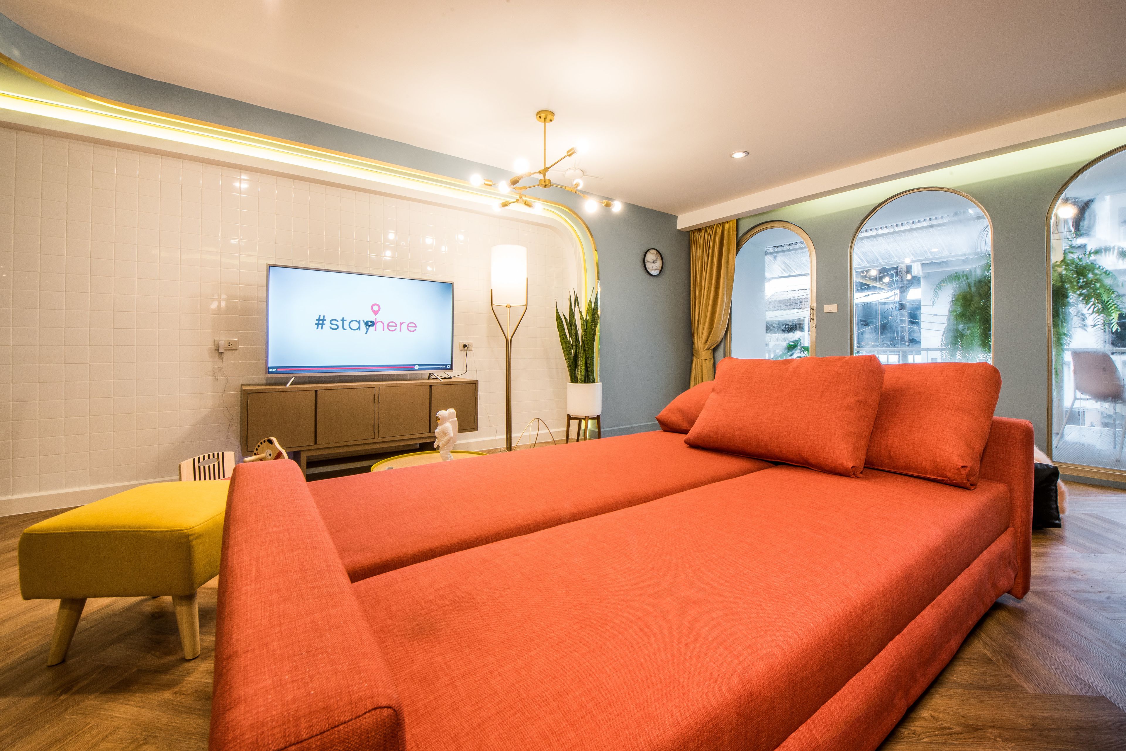 A modern hotel room with a large bed, a TV, a desk, and a view of the outdoors.