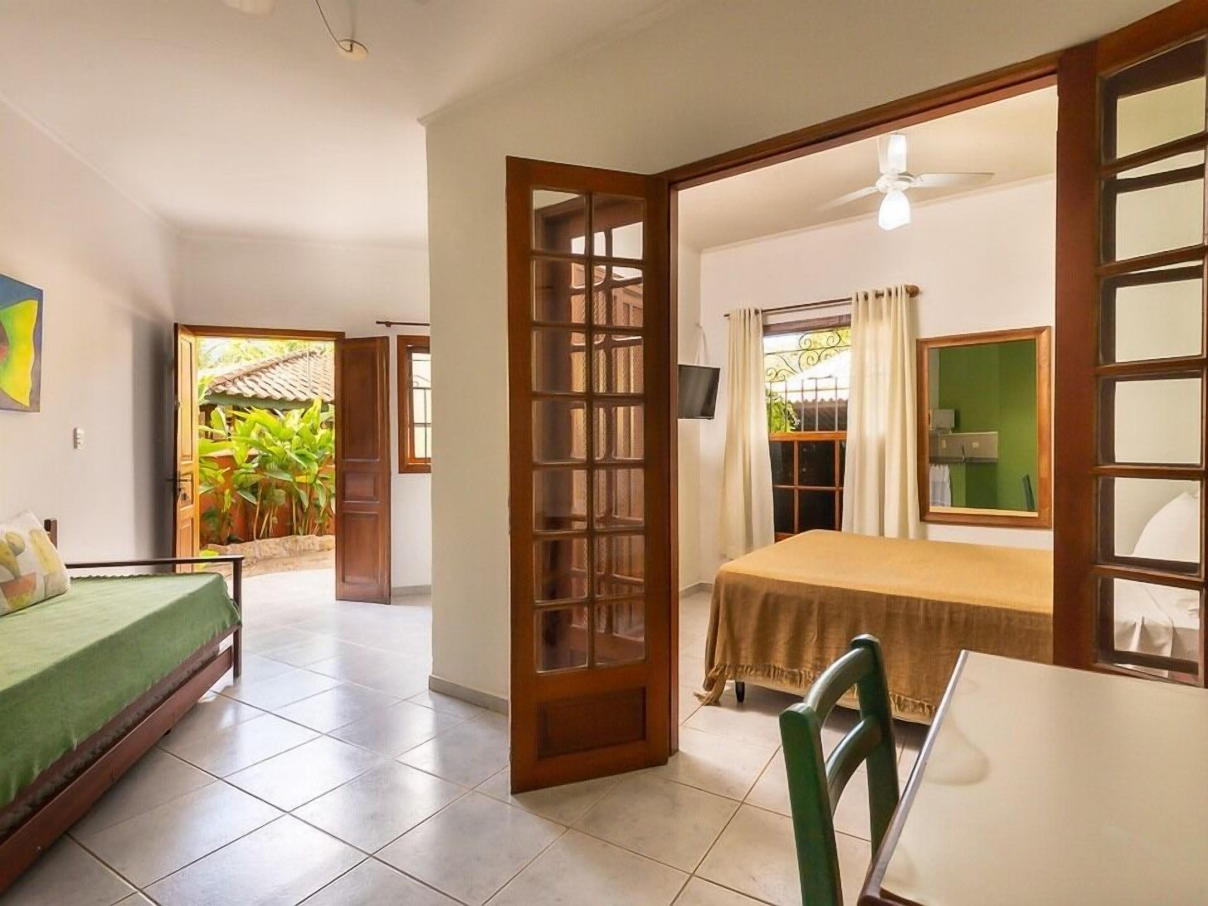 A room with a bed, a table, a chair, a TV, and a window with curtains.