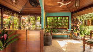 A wooden interior with a wooden reception desk, a bench, and a statue of a man on a skateboard. - Pousada Atiaia (Ilhabela)