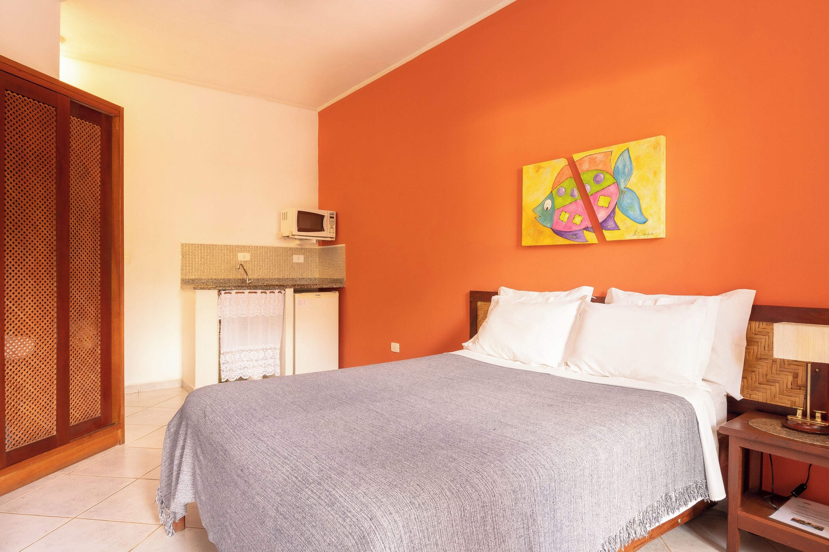 Een hotelkamer met een bed, een nachtkastje, een schilderij, een magnetron en een houten deur.