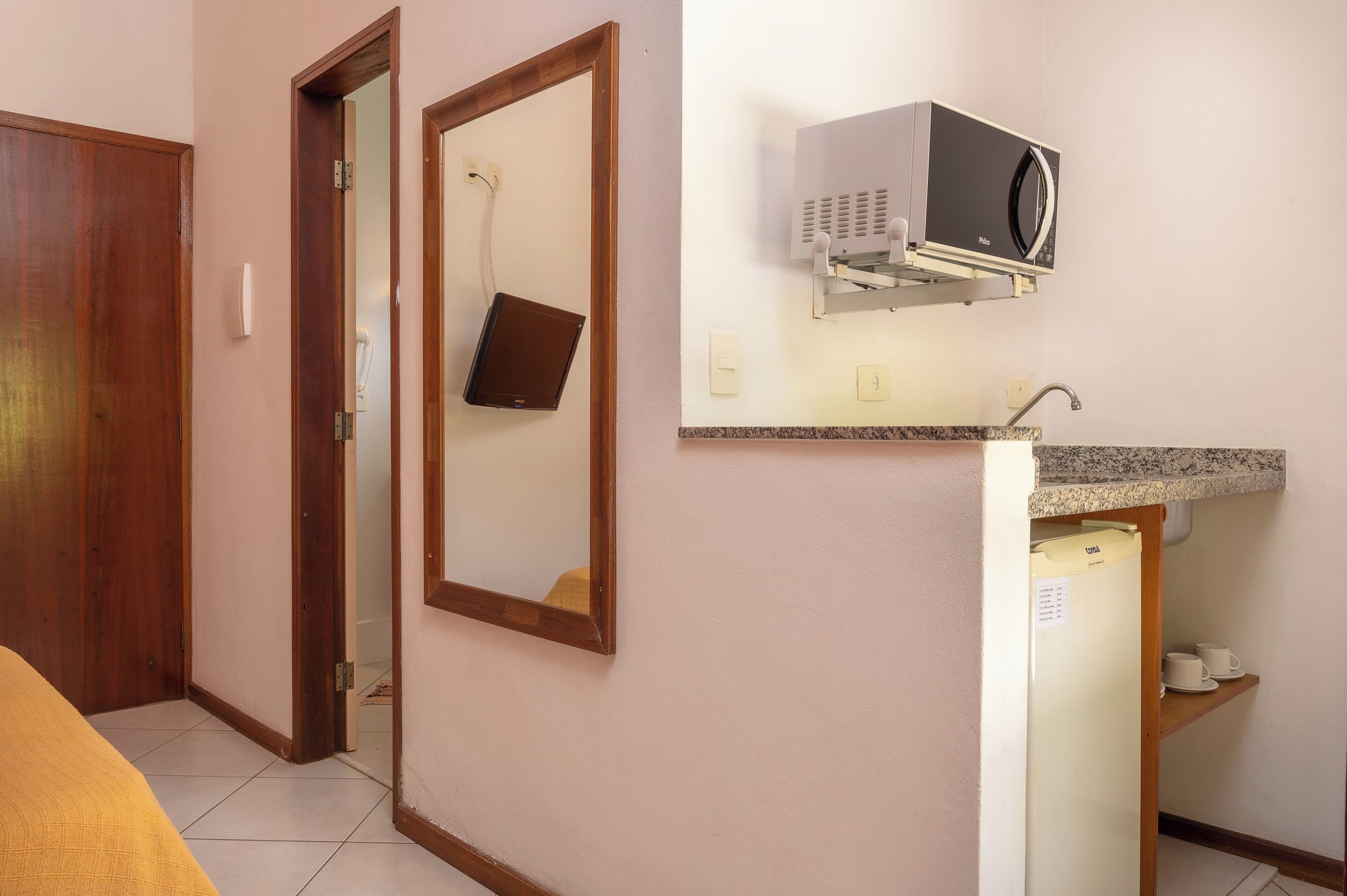 A compact kitchen with a microwave, a small refrigerator, and a countertop.