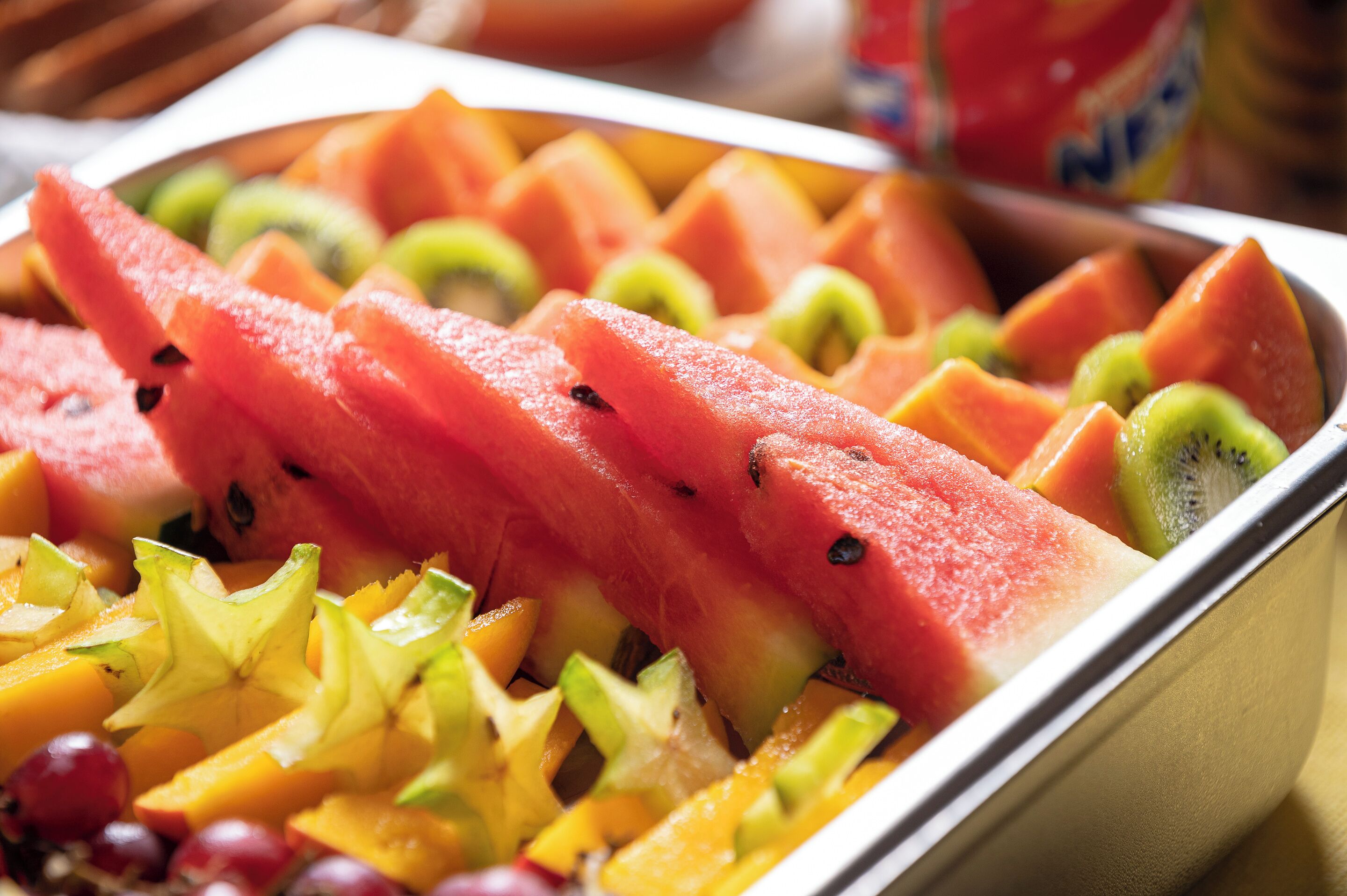 Une variété de fruits frais, notamment des pastèques, des kiwis, des mangues et des raisins, disposés sur un plateau.