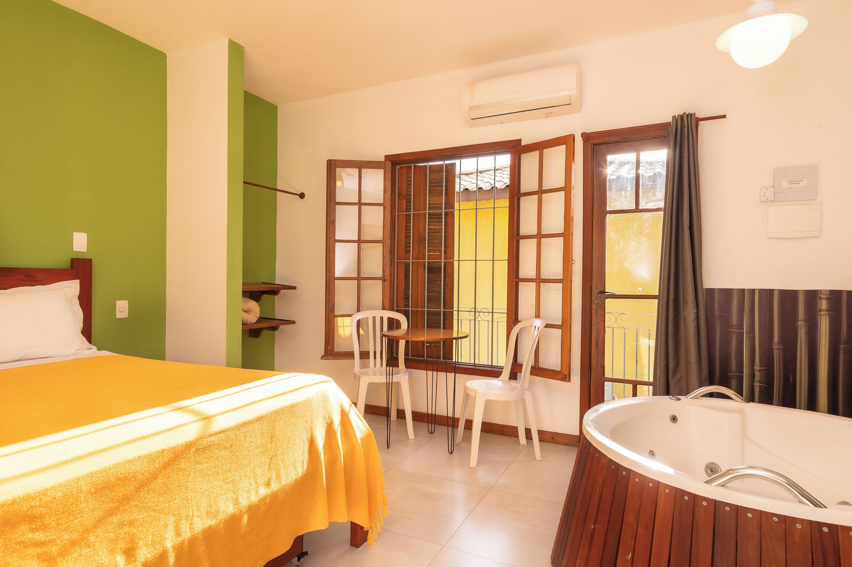 A hotel room with a bed, a table with chairs, a bathtub, and a window with a view.