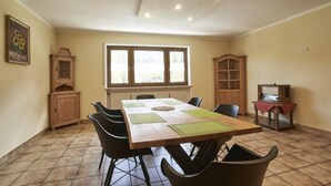 A dining area with a wooden table, black chairs, and a window with blinds. - Apartment Jenner, 1-4 persons, 135 sqm, 1 bedroom, terrace, near Königssee (Schönau am Königssee)