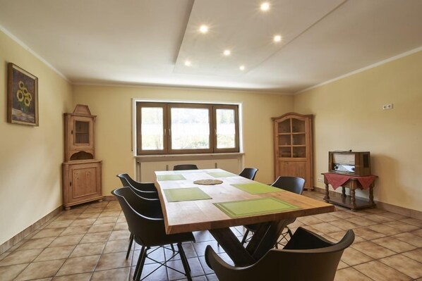 A dining area with a wooden table, black chairs, and a window with blinds.