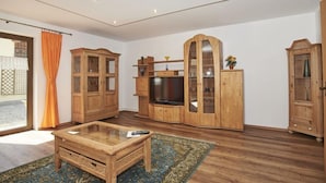 A living room with wooden furniture, a glass coffee table, and a television. - Apartment Jenner, 1-4 persons, 135 sqm, 1 bedroom, terrace, near Königssee (Schönau am Königssee)