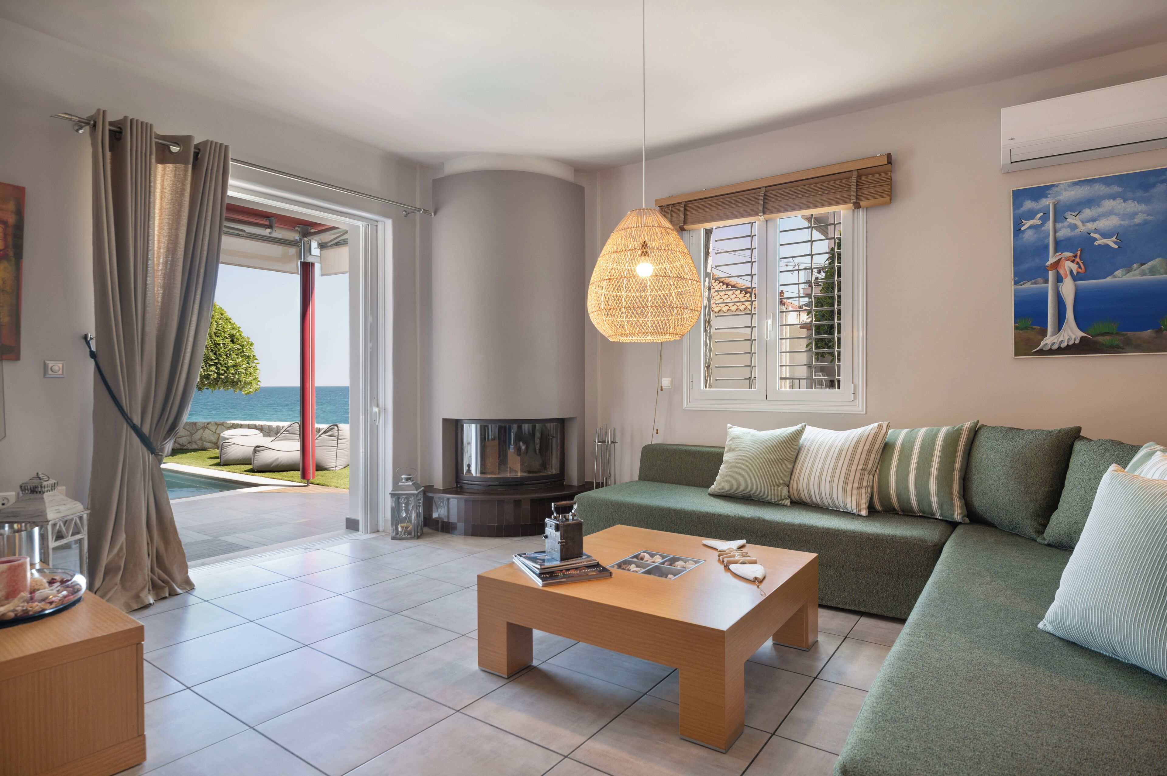 Ein Wohnzimmer mit einer Couch, einem Couchtisch, einem Kamin und Blick ins Freie.