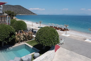 Zona de piscina con sillones, una bicicleta y vistas a la playa y al mar.