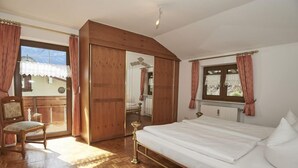Une chambre avec un plancher en bois, un lit, une chaise et un grand miroir.