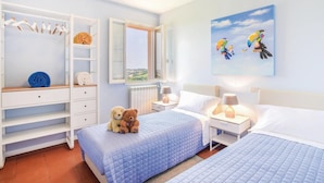 Een slaapkamer met twee bedden, een kledingkast, een raam met uitzicht en een schilderij aan de muur.