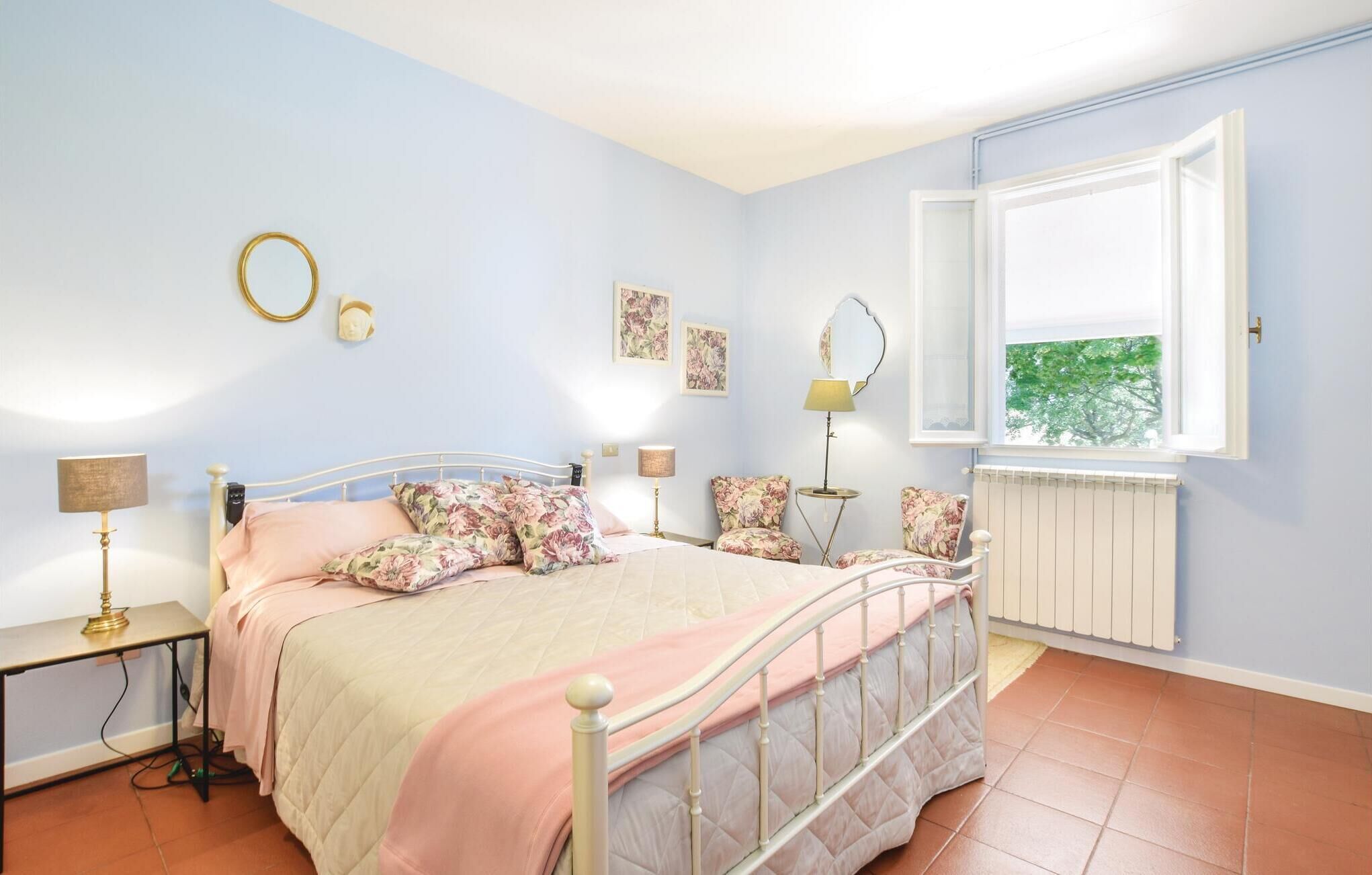 Une chambre à coucher avec un lit, des tables de chevet, une fenêtre et un radiateur.