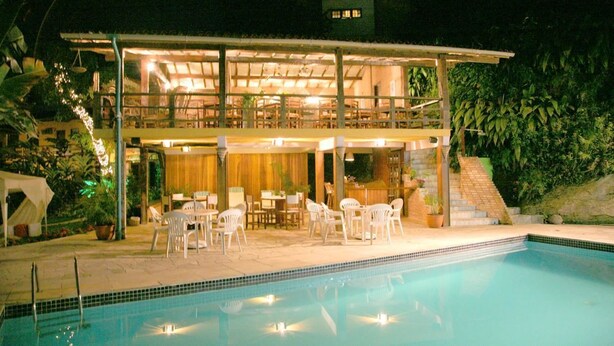 Ein zweistöckiges Gebäude mit Pool, Außenbereich zum Sitzen und einer überdachten Terrasse.
