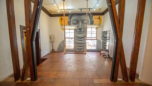 A spacious room with wooden flooring, a large window, and a mural of a face on the wall.