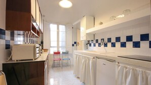 Eine Küche mit Toaster, Stühlen, Spüle und Fenster.