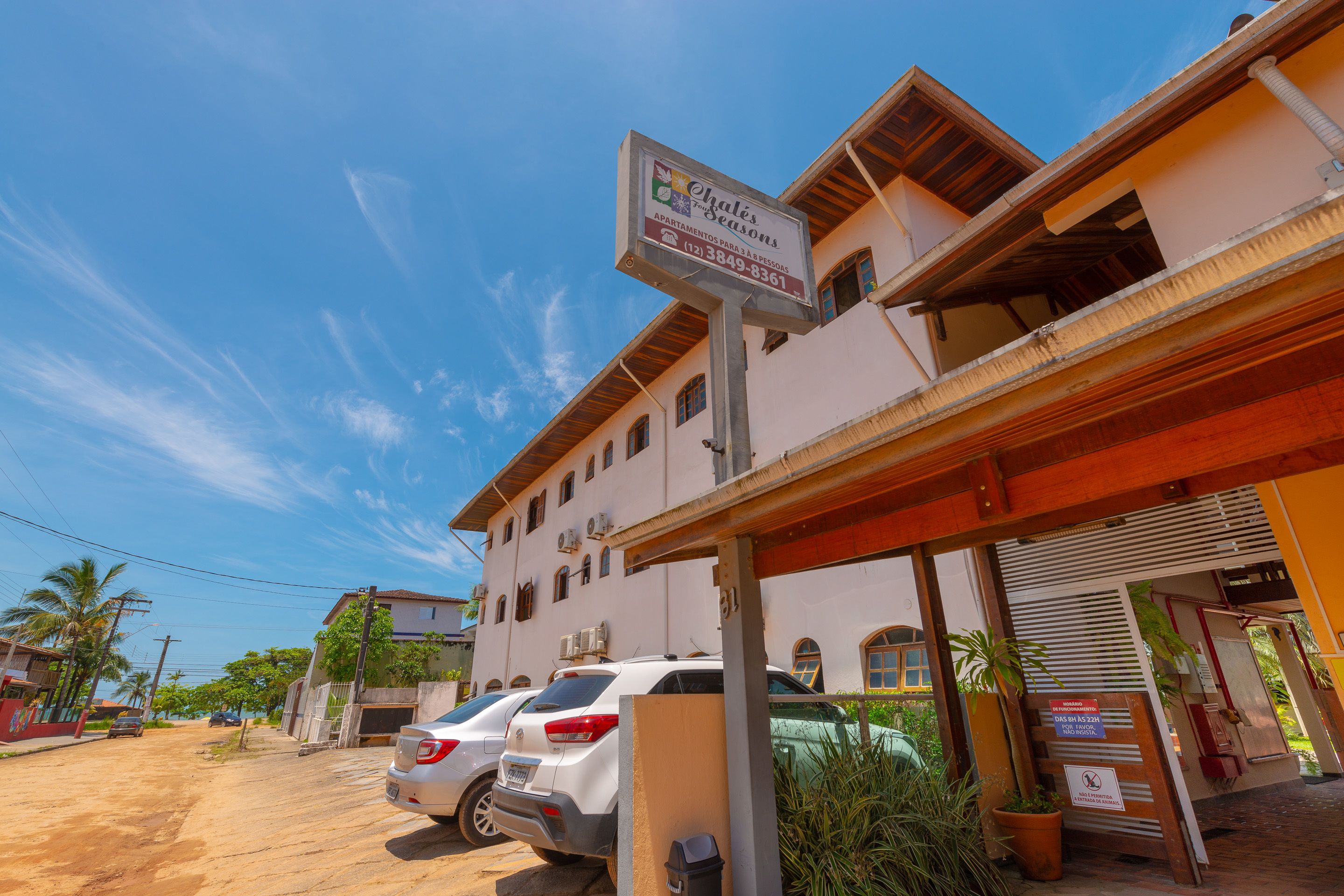 A building with a sign for "Ogles & Seasons" indicating it is a vacation rental. There are parked cars in front, and the building has a covered entrance.