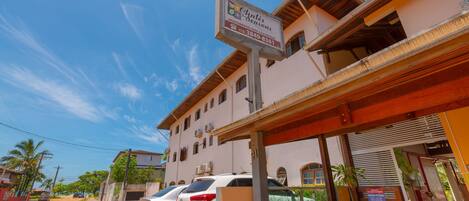 A building with a sign for "Ogles & Seasons" indicating it is a vacation rental. There are parked cars in front, and the building has a covered entrance.