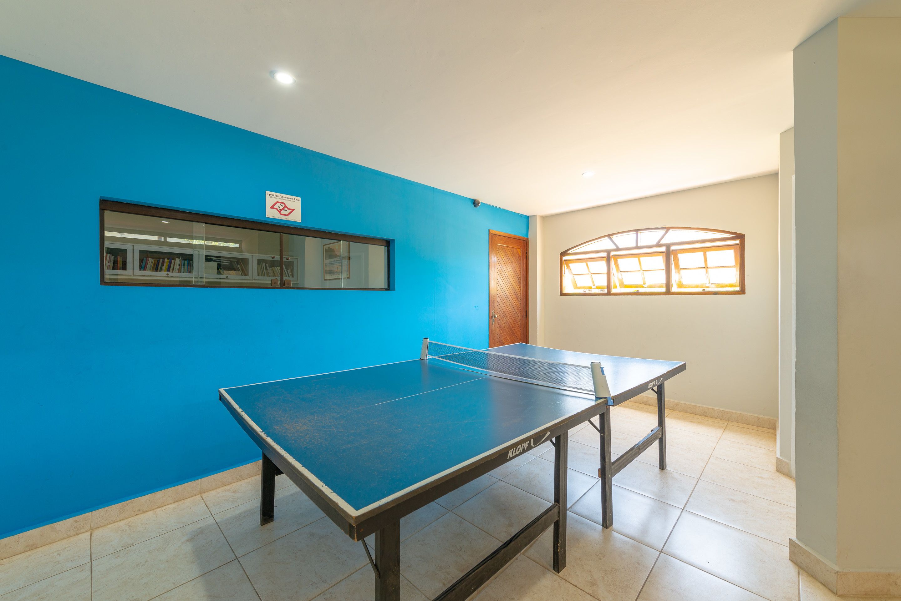 A room with a ping pong table, a window with a view, and a door.