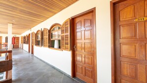 A hotel corridor with wooden doors numbered 311 and 310, and a bench on the left. - Chalés Four Seasons (Ubatuba)