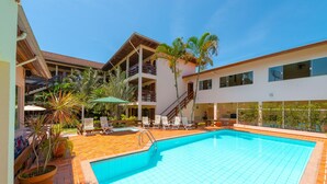 A swimming pool with tiled flooring, a staircase, and lounge chairs. - Chalés Four Seasons (Ubatuba)