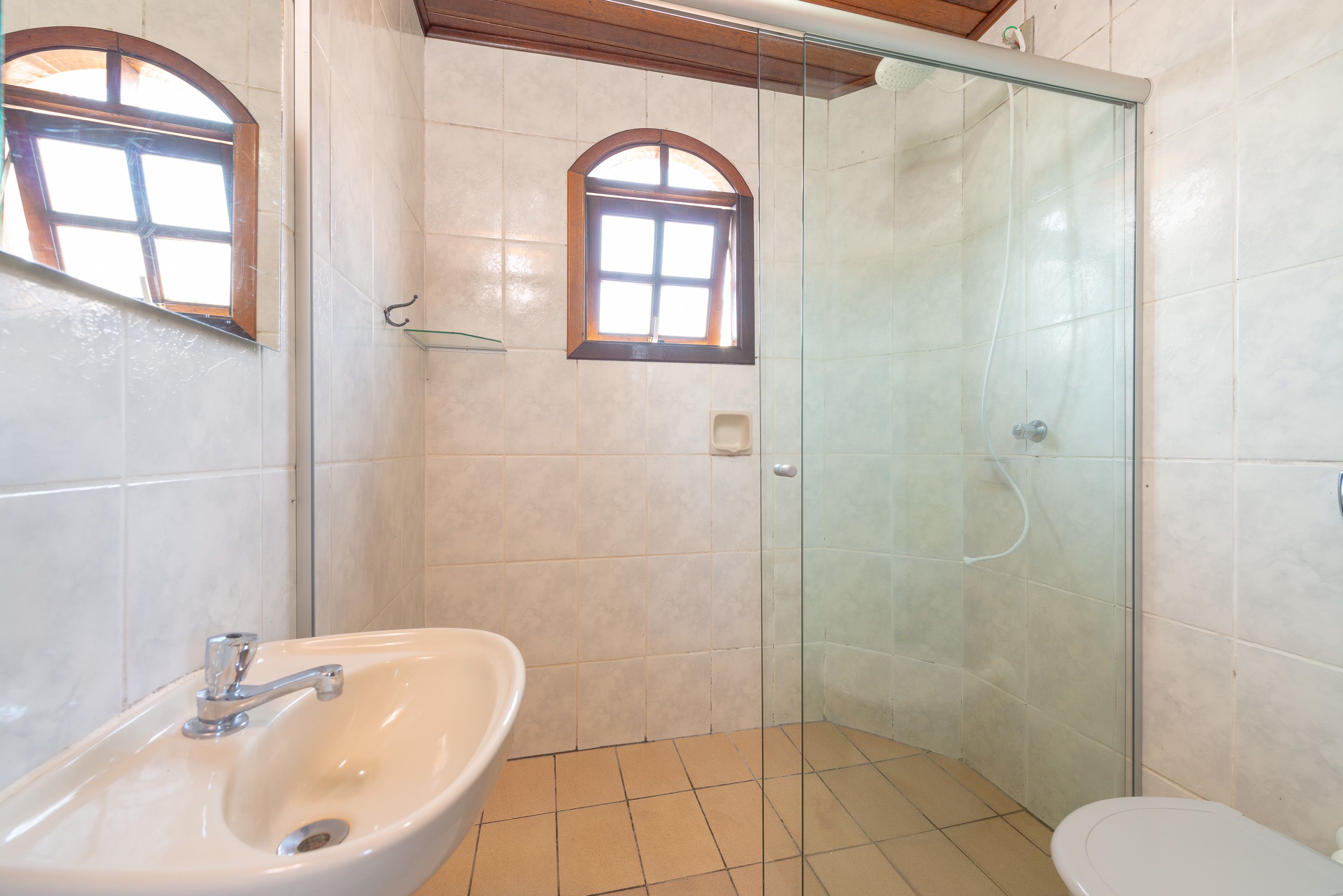 A bathroom with a glass-enclosed shower, a sink, and a toilet.