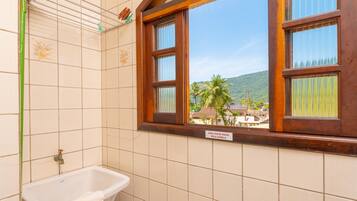 Un baño con ventana, lavamanos y toallero.