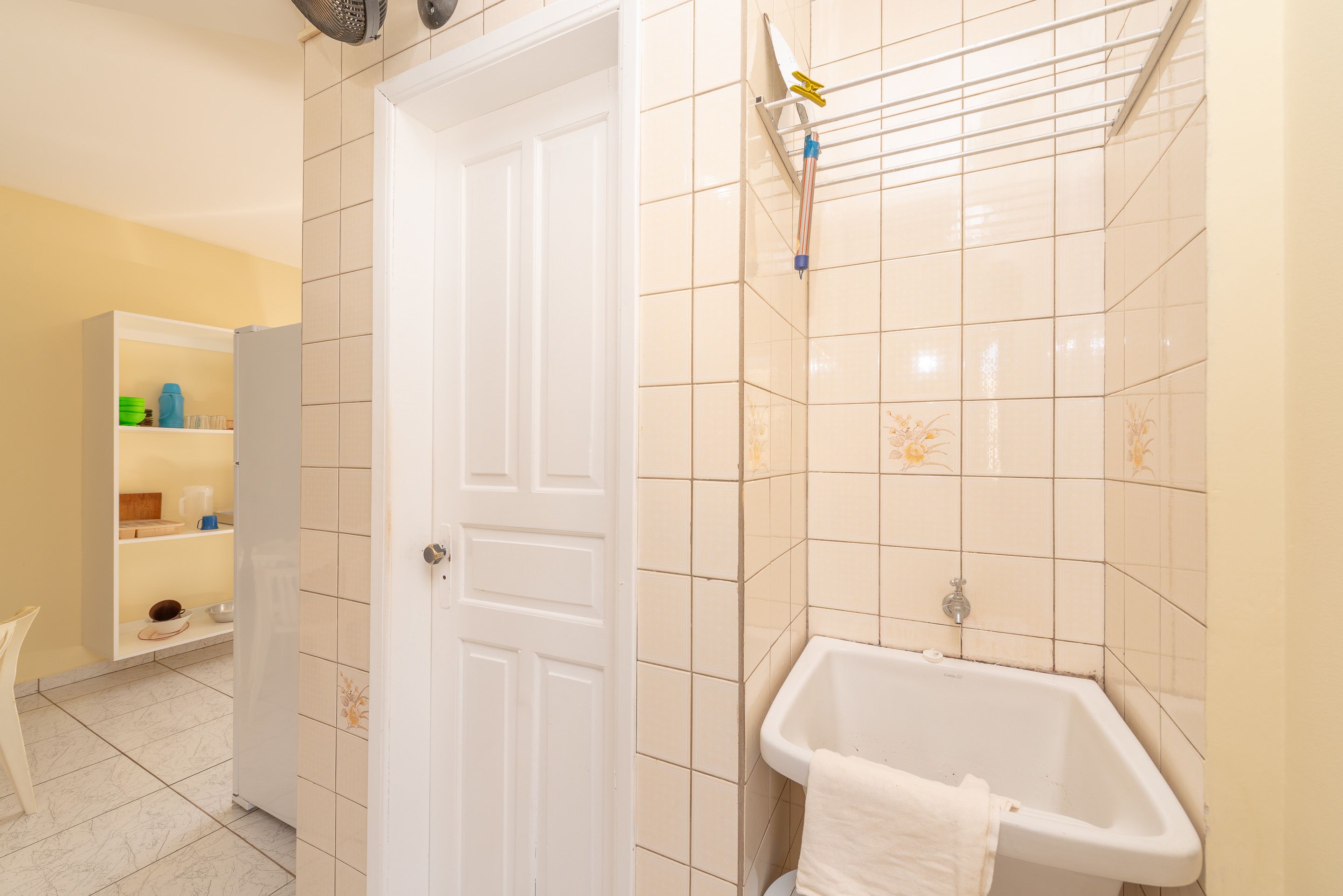 Un baño con una puerta blanca, una bañera y un estante con artículos de aseo.