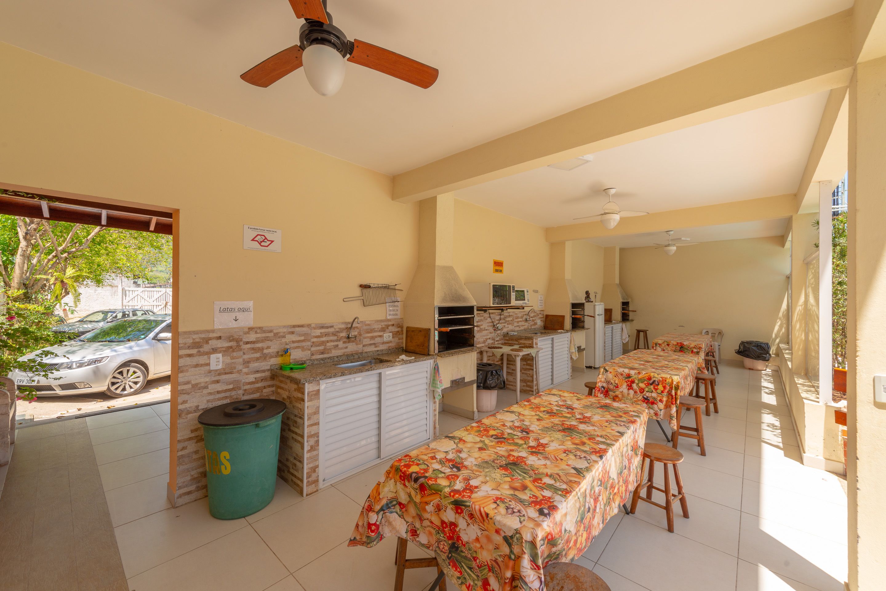 A spacious kitchen with a long counter, a dining area with a table covered in a floral tablecloth, and a ceiling fan.