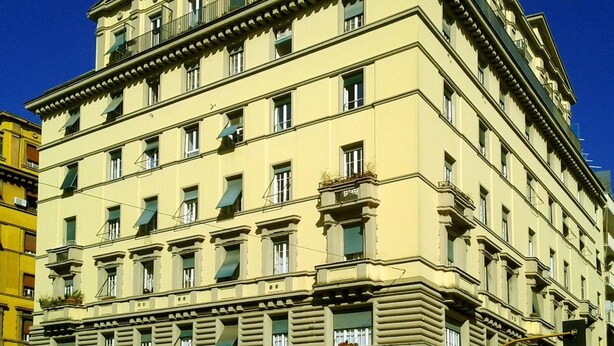 Un edificio de varios pisos con estilo arquitectónico clásico, que presenta una fachada simétrica con ventanas regularmente espaciadas y detalles decorativos.