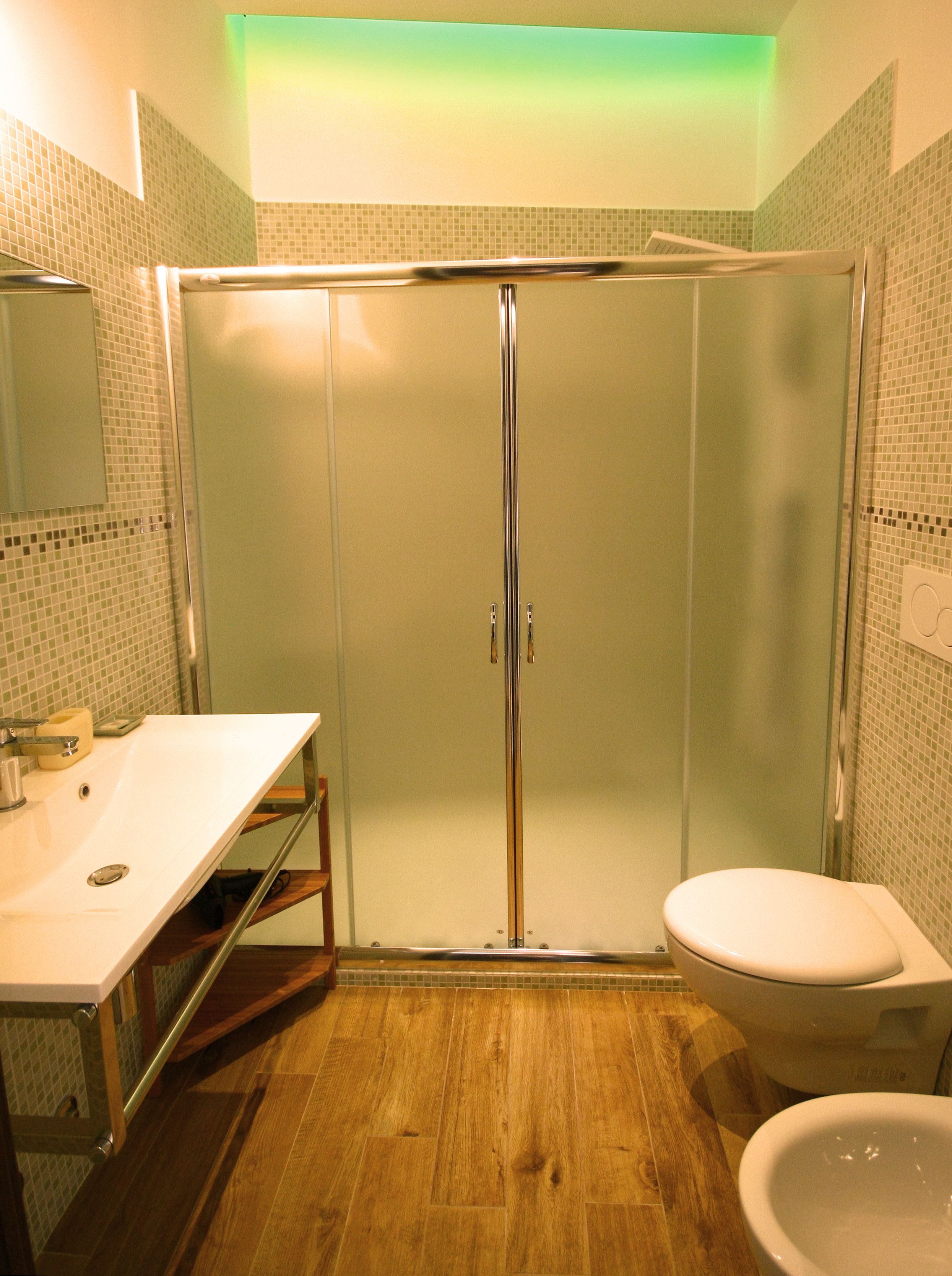 A bathroom with a glass shower enclosure, a sink, a toilet, and a mirror.