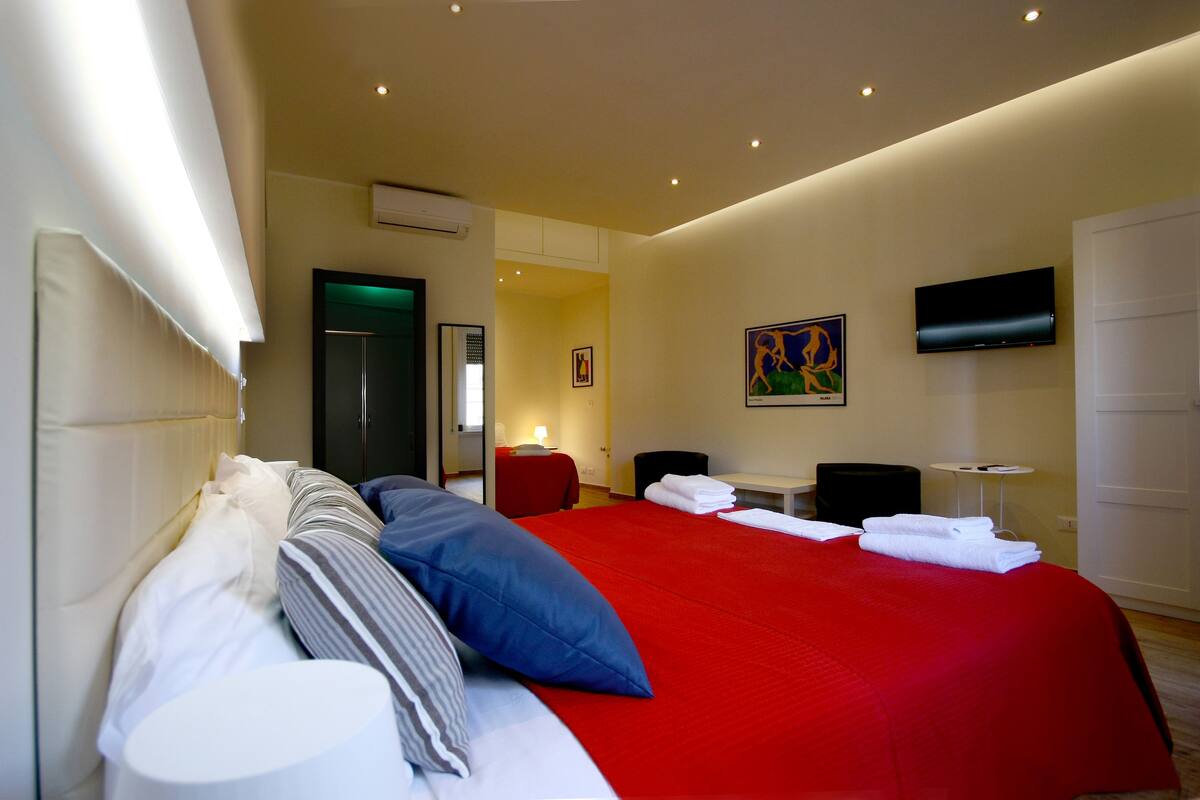 A hotel room with a large bed, a flat-screen TV, a desk, and a chair.