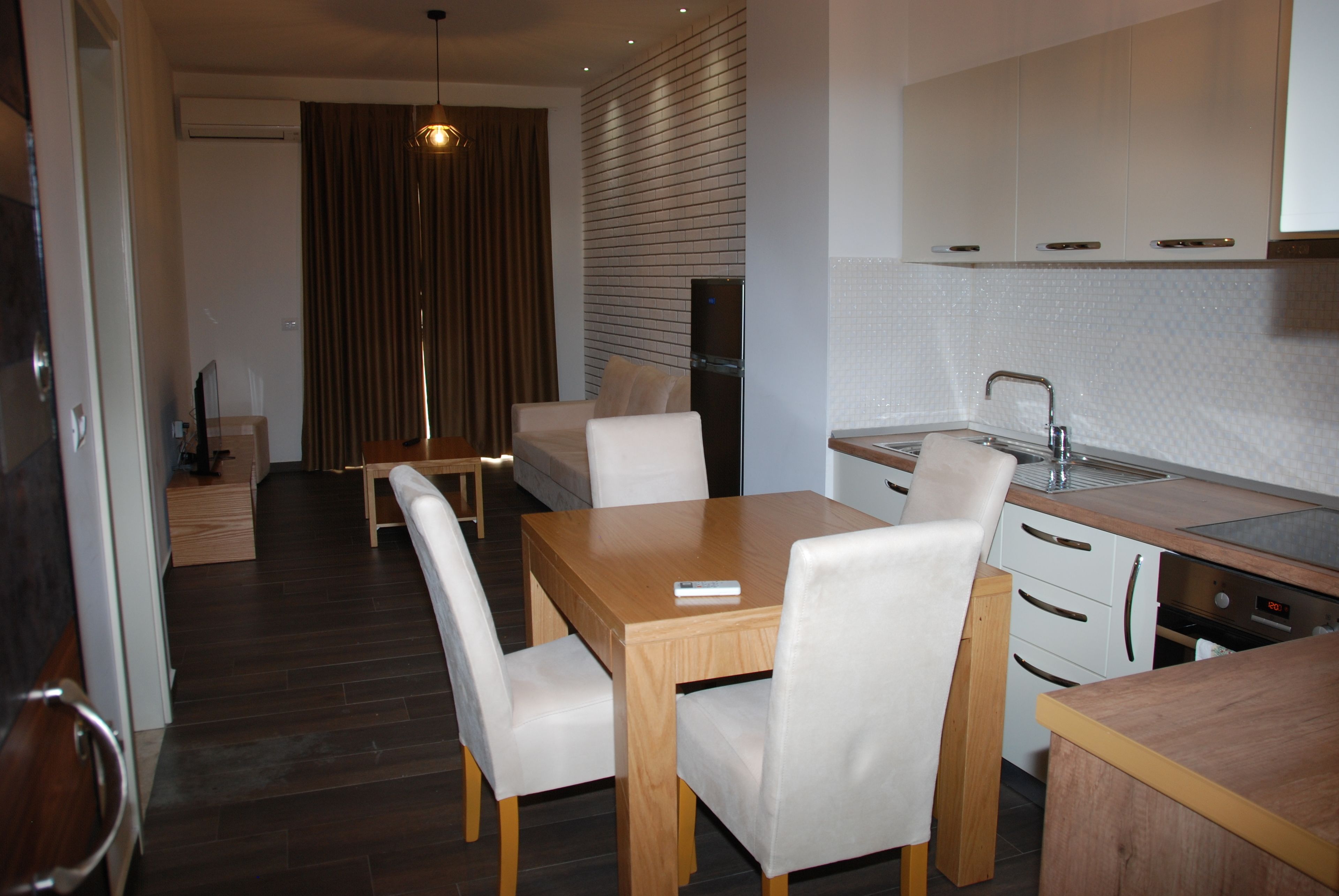 A modern kitchen with white cabinets, a wooden dining table, and white chairs.